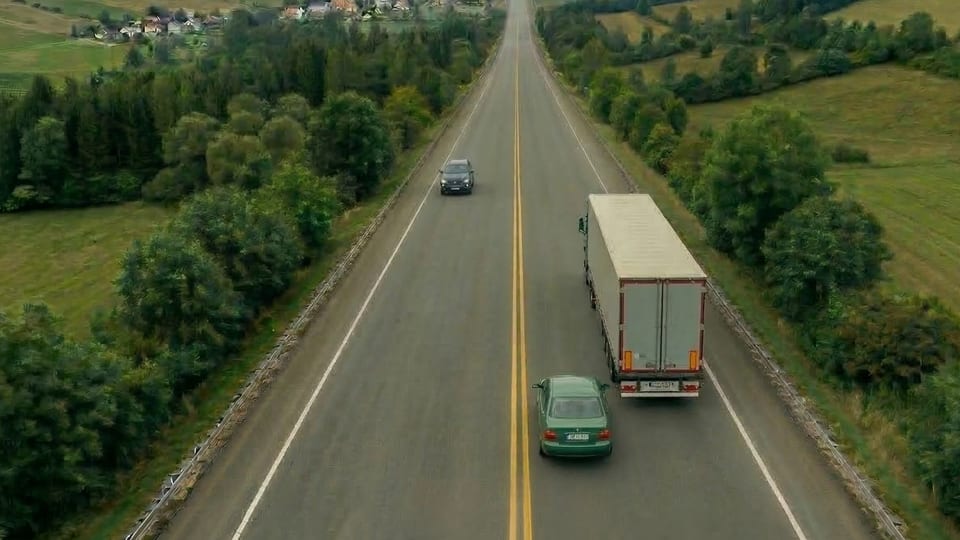A car preparing to pass a truck on a two-lane road