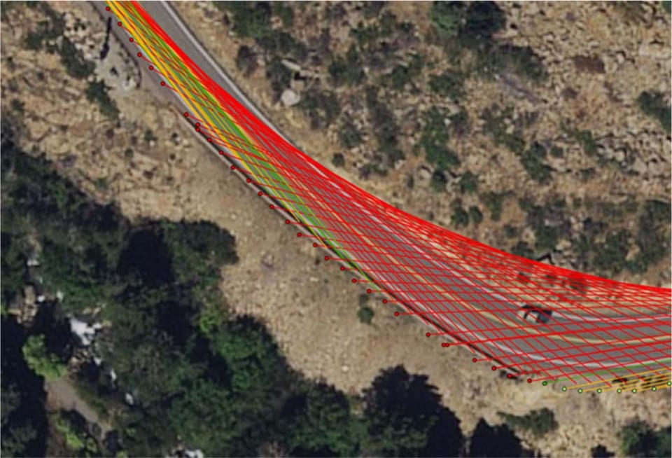 An aerial view of a curving mountain road with sight lines drawn from each point on it: green and yellow where the view is clear, red where it is restricted